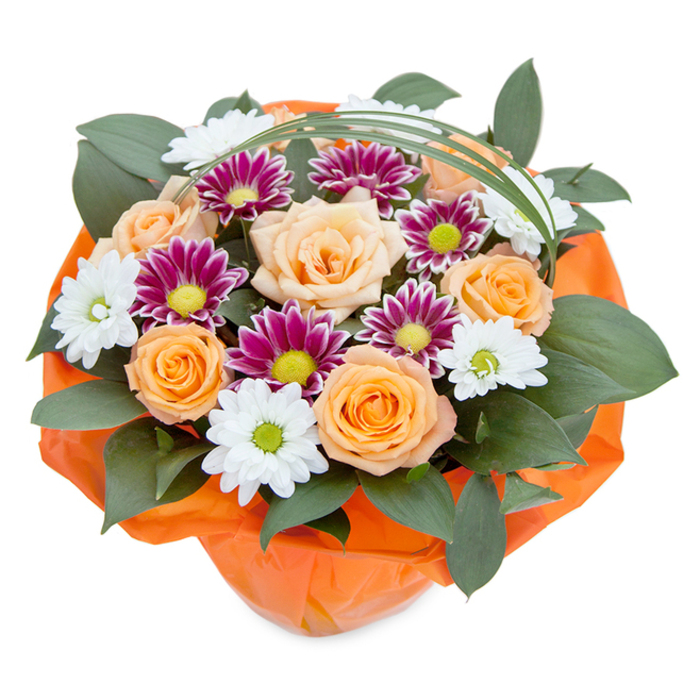 Brimming with warmth and thoughtfully composed, this striking bouquet chosen from Dalston Flowers reveals its artistry from an overhead vantage, with each blossom presented against a bright, neutral background. The centerpiece-a harmonious cluster of peach and orange roses-unfurls its soft, velvety petals, lending a classic romance and subtle fragrance that echo through nearby streets and cafes. Interwoven between the roses, clusters of chrysanthemums bring dynamic contrast: crisp white, daisy-like flowers radiate from spring-green centers, imparting freshness and delicacy, while magenta-purple chrysanthemums stand out for their complex petal structure and luminous lime centers. Lush, glossy greenery-likely local ruscus or broad-leafed foliage-emerges generously from beneath, supporting the bouquet's depth and fullness, much like Dalston's close-knit community spirit. Gracing the peak, a slender arch of bright green decorative grass adds a hint of contemporary elegance and gentle movement, recalling the artistic pulse thriving throughout East London. The bouquet is neatly bound in vibrant orange cellophane, textured and luminous, which echoes and elevates the bouquet's warm hues, ready for gifting in celebration of anything from a milestone to an ordinary Dalston day turned extraordinary. Every petal, leaf, and wrapping resonates with expert care and a genuine love for craftsmanship, offering up a bouquet that truly captures the charm and joy of Dalston living.